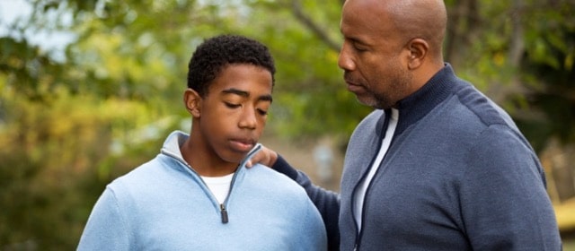 A father touching his son's shoulder showing support and encouragement