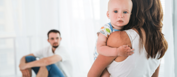 Father looking at mother who is holding a sad baby