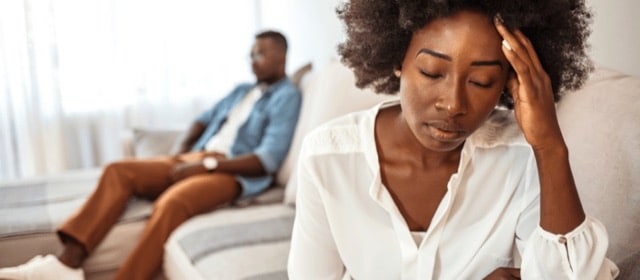 A woman seated on a couch, her head in her hands, expressing feelings of stress about divorce