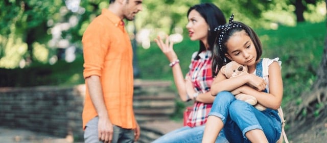 parents argue while sad child hugs teddy bear