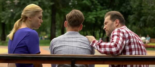 teenager sitting on bench with both parents