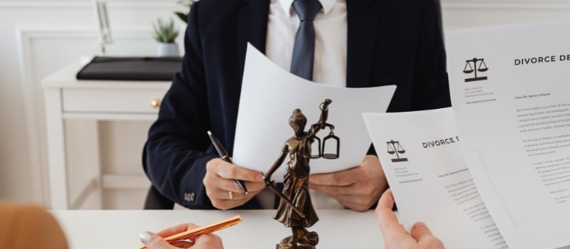 A lawyer in a suit holds divorce papers while meeting with clients, helping answer the question, what is uncontested divorce?