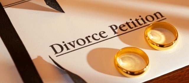 A paper of divorce petition with wedding rings placed on top