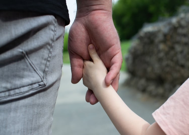 father with sole custody holds the child's hand